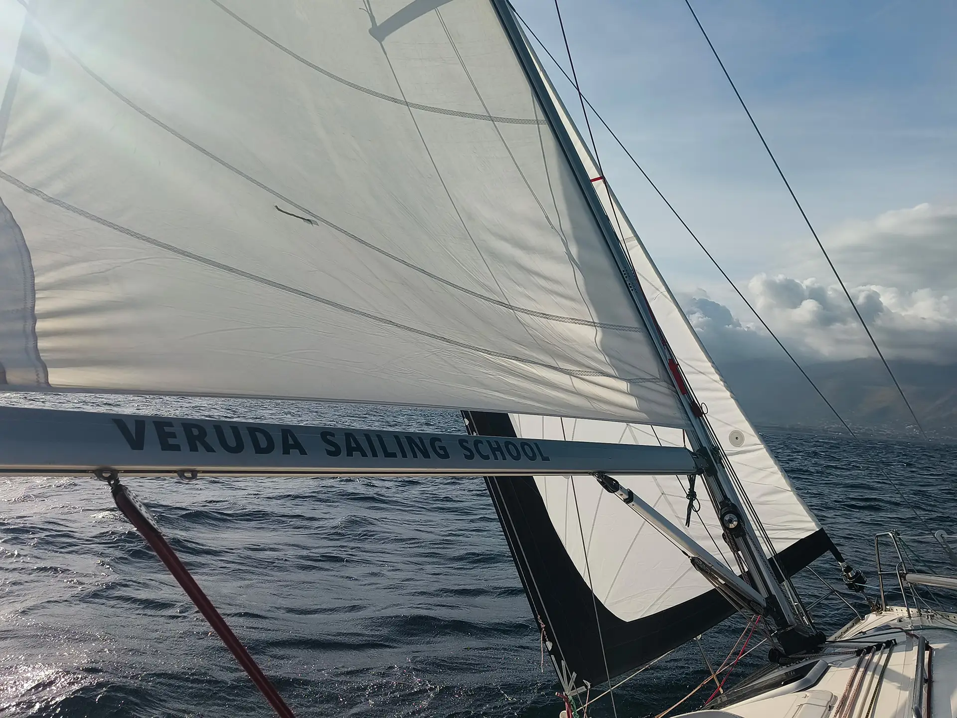 Sailboat beating upwind across the open Balearic Sea under winter skies