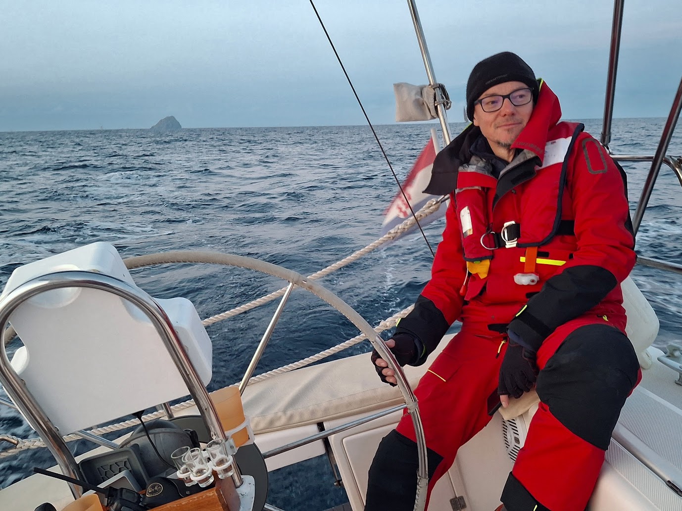 Robert Šarić, experienced skipper and instructor at Veruda Sailing School, smiling at the helm of a sailboat on an offshore sailing adventure.